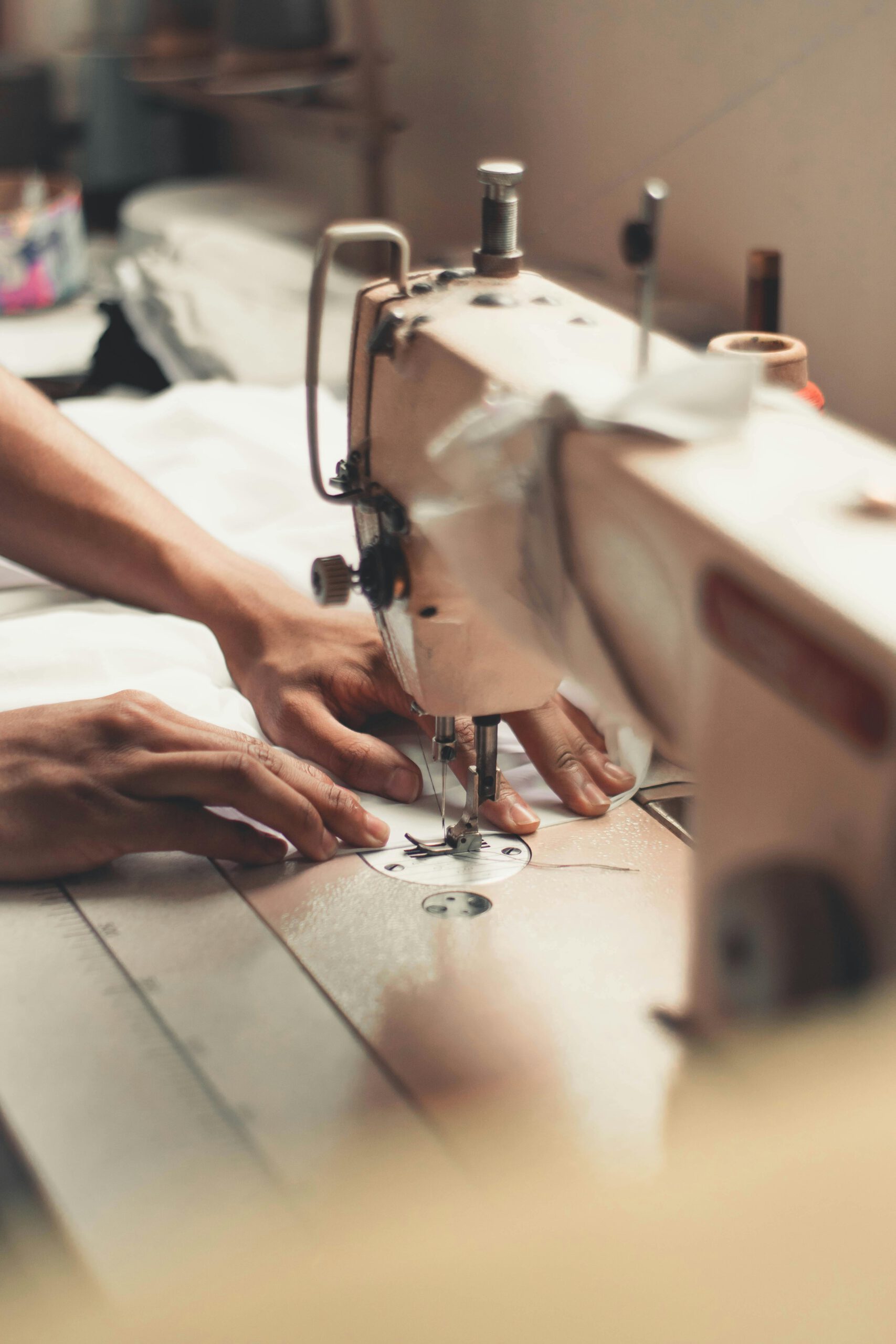 pexels-photo-2973392-2973392 Close-up of hands using a sewing machine, depicting craftsmanship and textiles indoors.